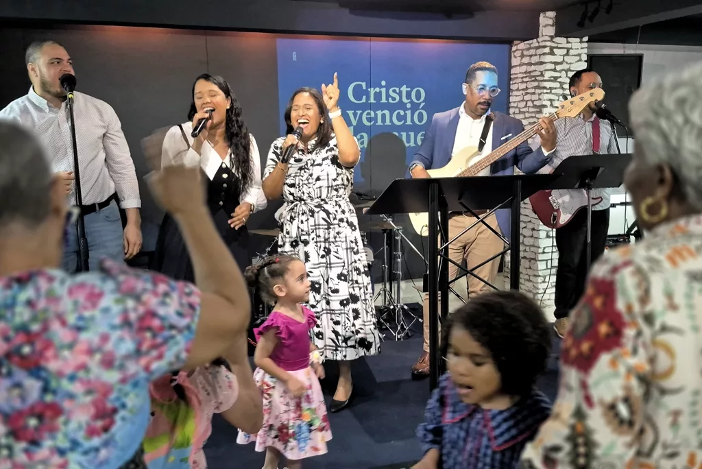 Personas de pie cantando durante la reunión del domingo