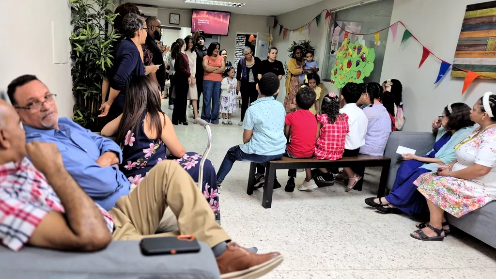 Personas sentadas en la sala mientras los niños miran la pantalla